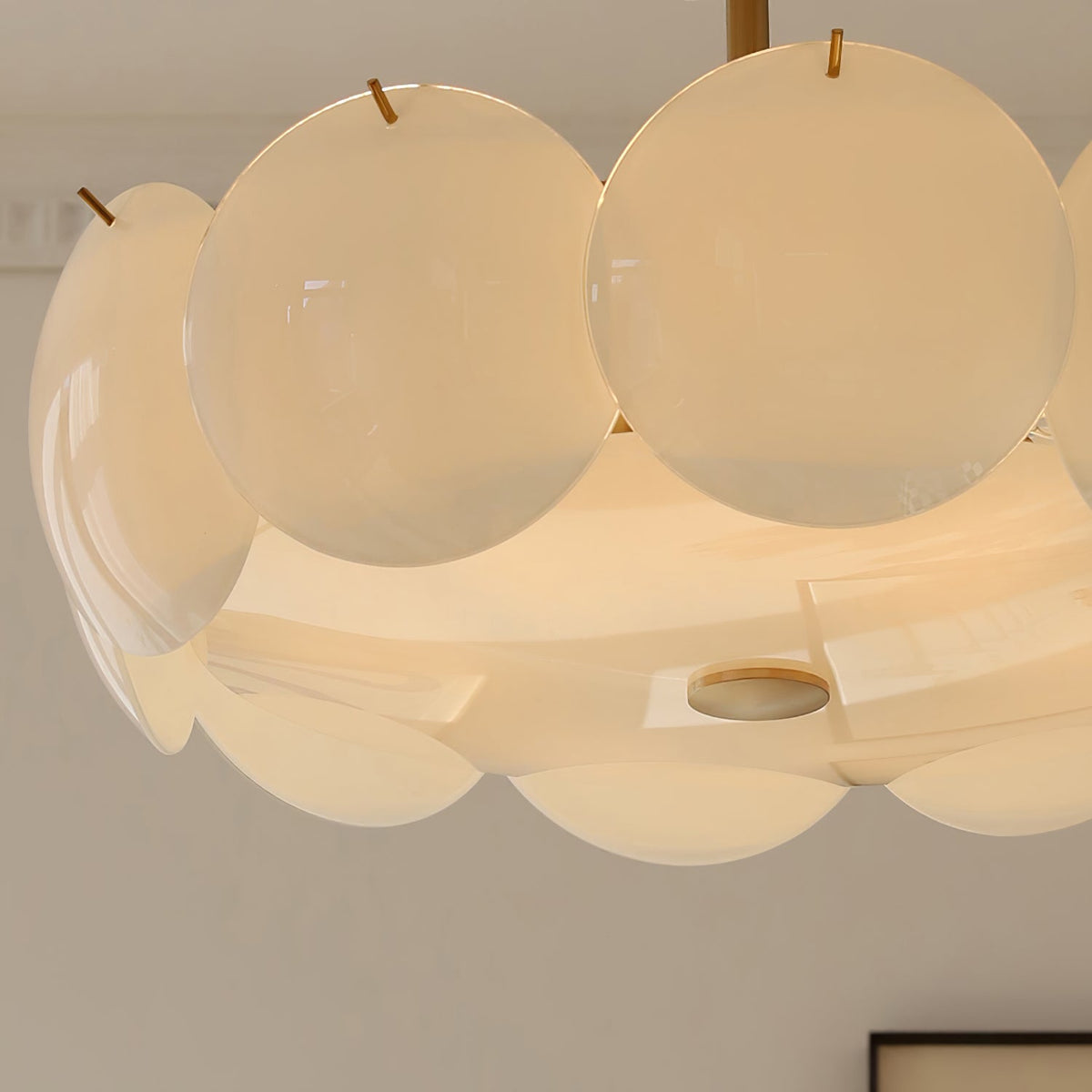 Close view of the round frosted shades, small brass pins and the brass disc on the underside of this Clérachic chandelier.