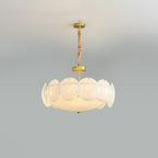 Clérachic chandelier on a twisted chain below a pale ceiling, lit, with a ring of round white shades around a glowing centre.