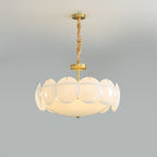 Straight-on view of the lit Clérachic chandelier, brass stem and chain above overlapping white shades, on a soft grey backdrop.