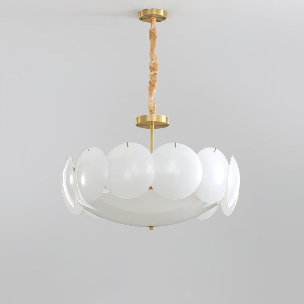 Unlit Clérachic chandelier with frosted white shades on a brass stem and chain, shown against a pale grey backdrop.