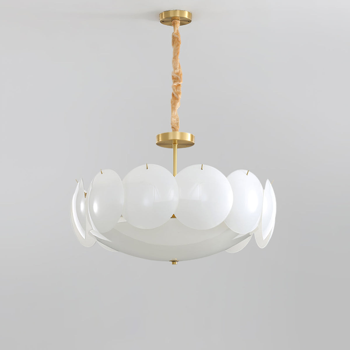 Unlit Clérachic chandelier with frosted white shades on a brass stem and chain, shown against a pale grey backdrop.