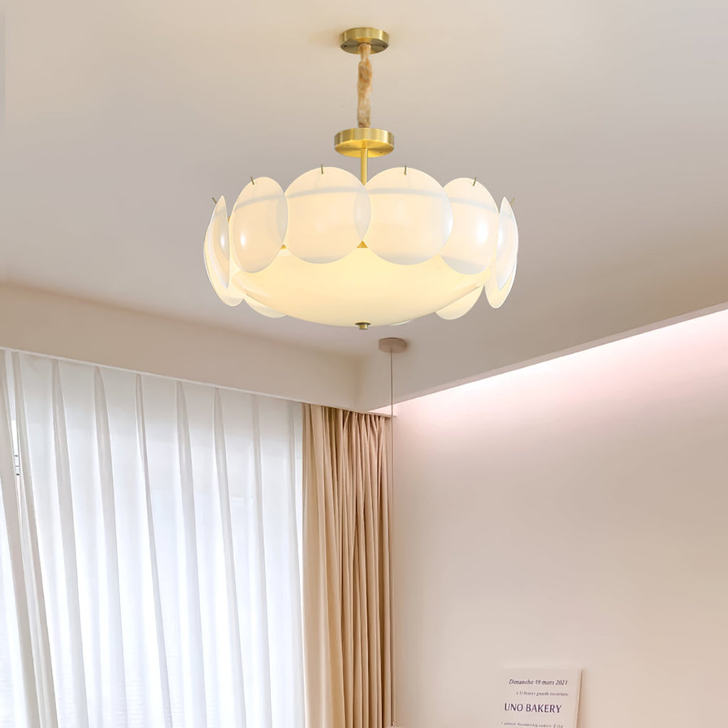 Clérachic chandelier lit and hanging high in a room with white curtains, gold drapes and a pink-washed cove ceiling.