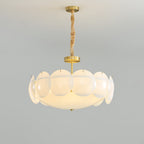 Lit Clérachic chandelier on a twisted chain, its layered shades glowing warm against a pale grey wall.