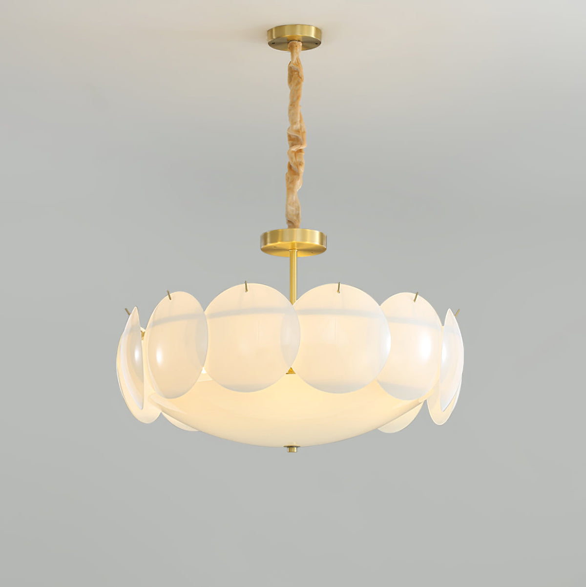 Lit Clérachic chandelier on a twisted chain, its layered shades glowing warm against a pale grey wall.