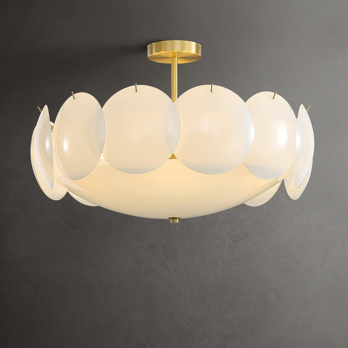 Semi-flush Clérachic chandelier lit against a dark grey wall, with a short brass stem above wide frosted shades.