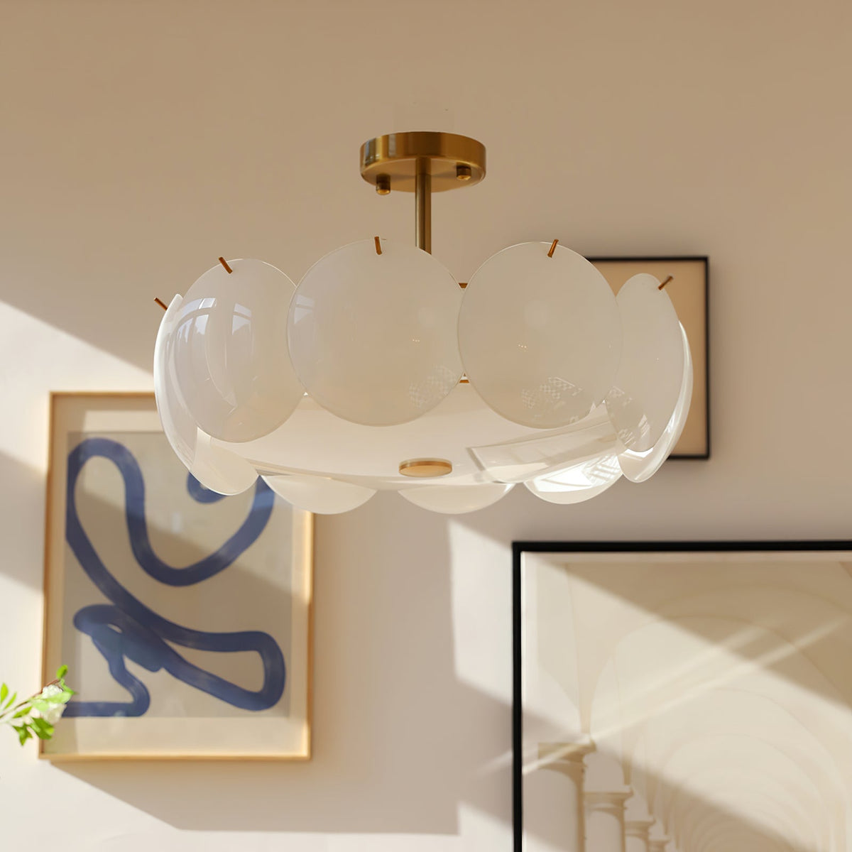 Clérachic semi-flush chandelier in warm daylight, its layered shades beside a framed blue squiggle print and a second frame.