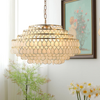 Lit warm beside a framed painting and a bunch of white narcissi, this Clérachic chandelier shows rings of teardrop shell discs on gold.