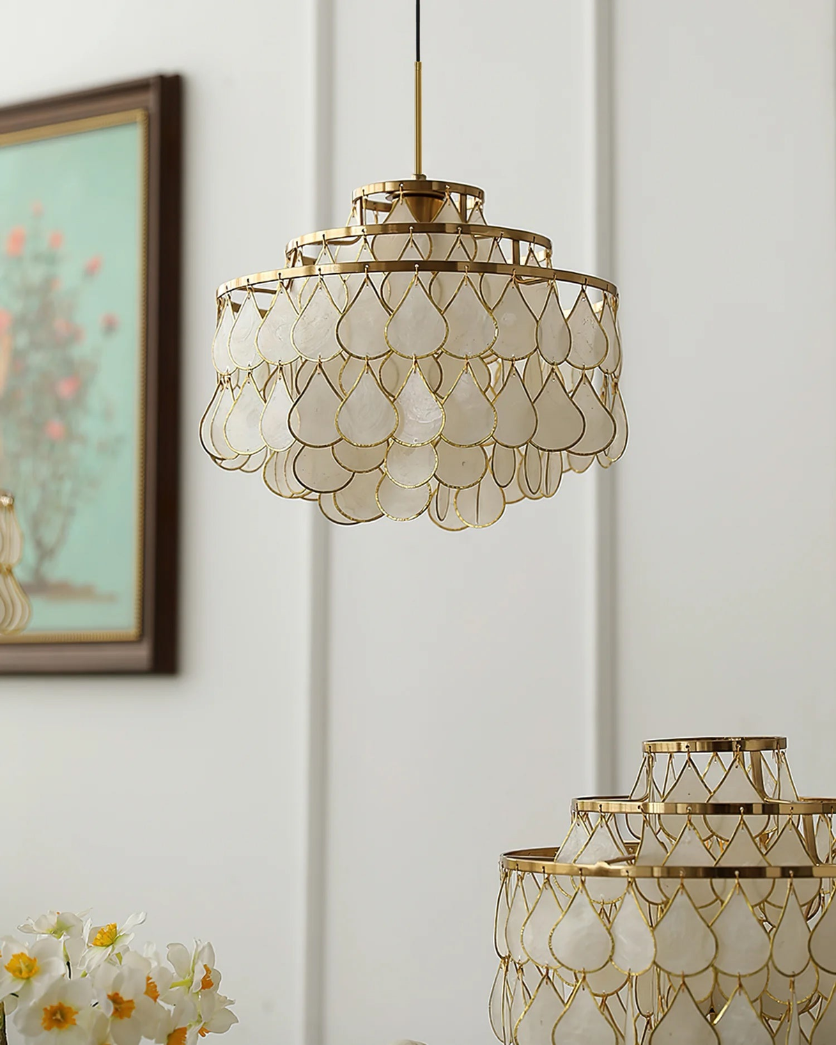 Unlit in daylight, this Clérachic chandelier shows pearly capiz shell teardrops in gold wire frames, with a second fitting below it.