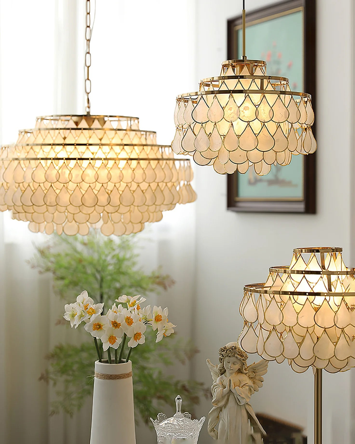 Several Clérachic chandeliers near a vase of narcissi, with the closest in the upper left and a floor lamp version at lower right.
