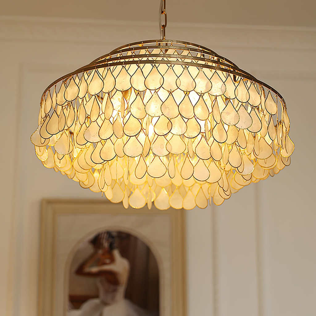 This Clérachic chandelier lit and seen from below, its gold-framed teardrop shell discs glowing warm in front of an arched painting.