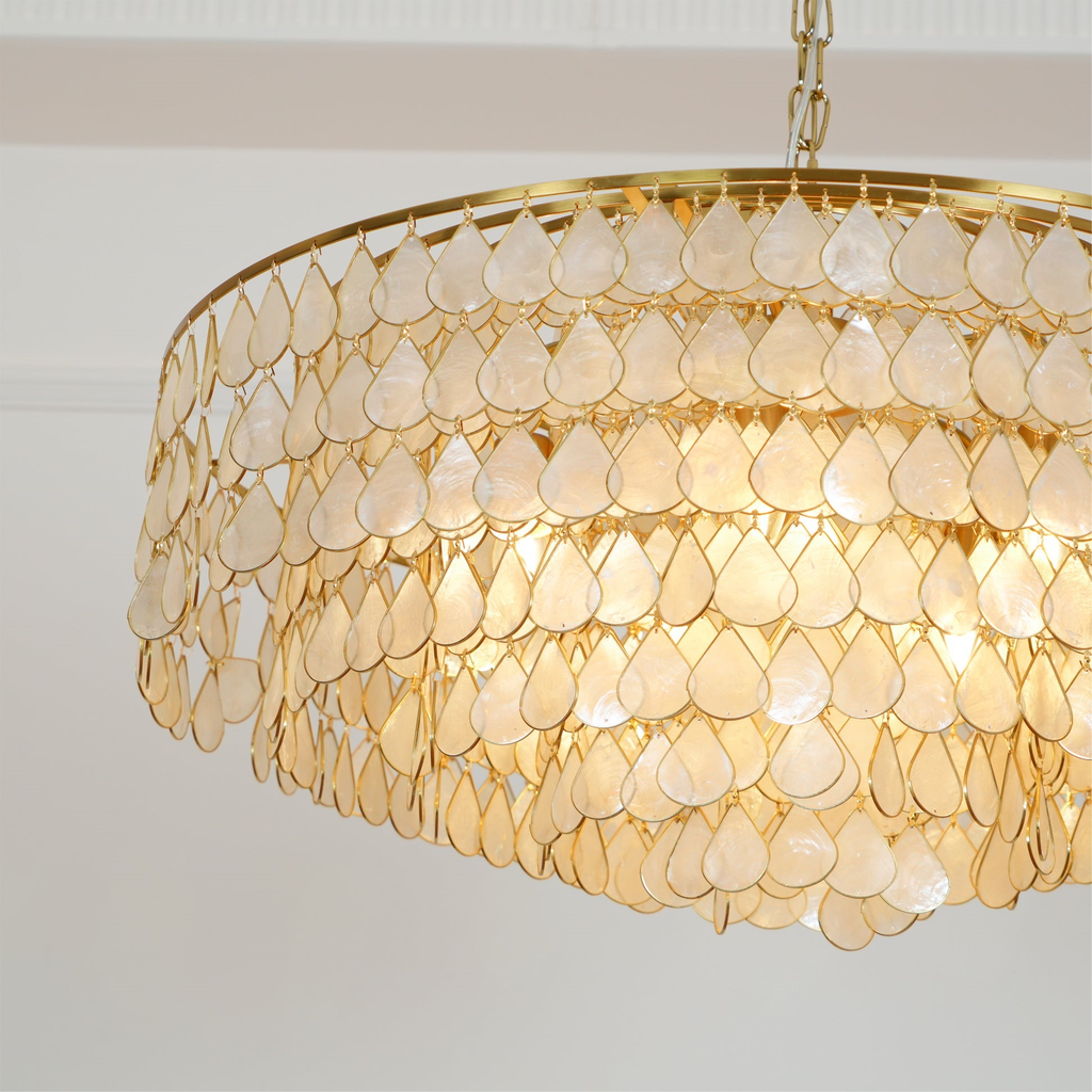 Seen from the side, this Clérachic chandelier shows layers of pale shell teardrops hung from wide gold rings, with a chain above.