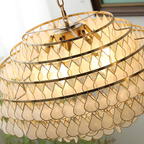 Looking up into this Clérachic chandelier, the gold rings, the top plate and the shell teardrops show glowing warm inside.