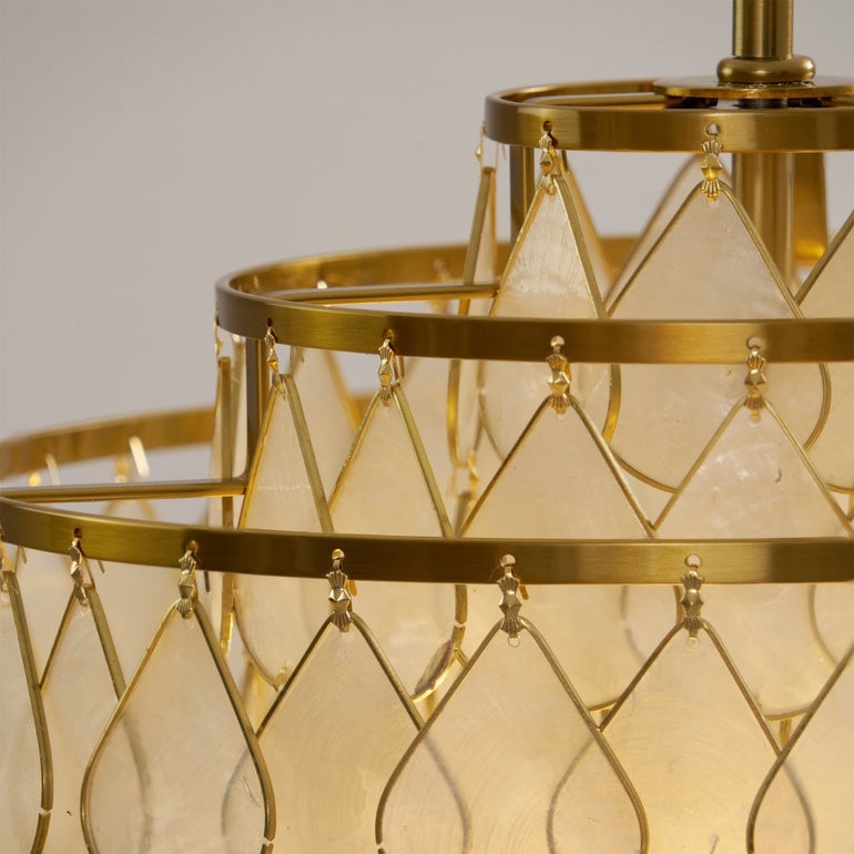 Close view of the gold rings and wire frames on this Clérachic chandelier, with warm light behind the shell teardrops.