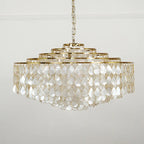A wide Clérachic chandelier on a chain and gold canopy, with five tiers of pearly shell teardrops on a pale grey wall.
