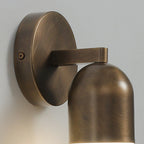 Close view of the round backplate, fixing screw and arm of this antique brass Clérachic wall light.