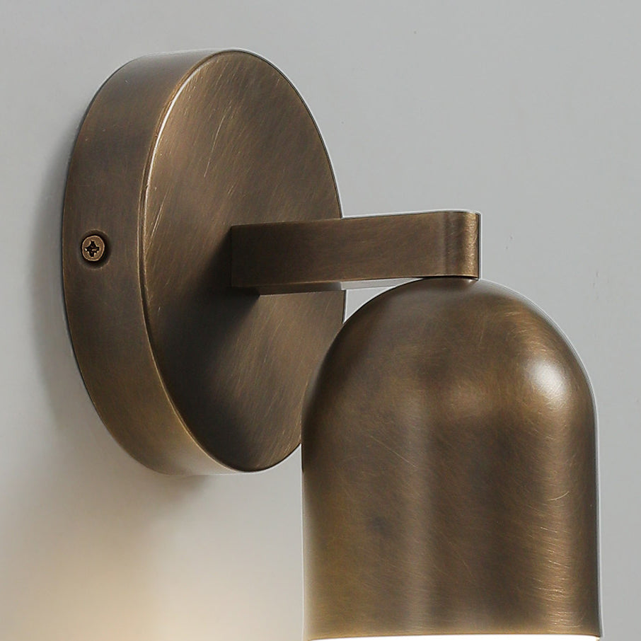 Close view of the round backplate, fixing screw and arm of this antique brass Clérachic wall light.