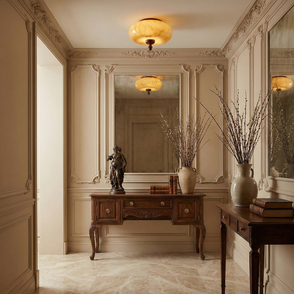 Two reflections of this Clérachic caramel glass ceiling light, one hanging in a panelled hallway and one in the mirror over a carved wooden console.