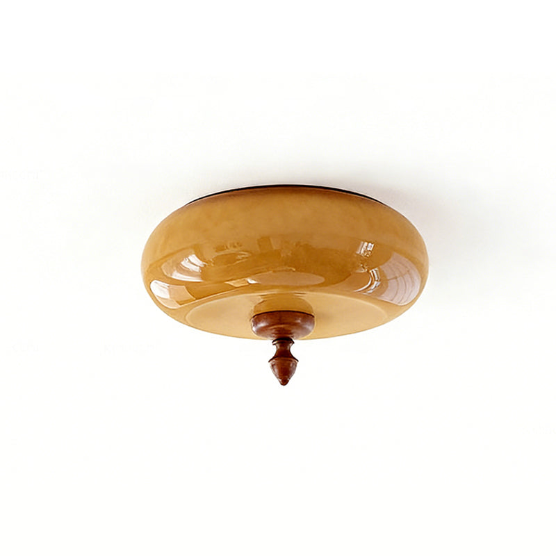 Angled view of the caramel glass dome and walnut-toned finial of this Clérachic ceiling light on a soft white background.