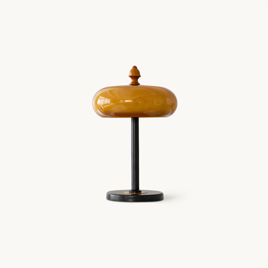 Caramel glass dome table lamp from Clérachic on a plain white backdrop, with a wooden finial, a slim black stem and a round black base.