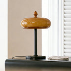 Unlit Clérachic dome lamp seen straight on, its glossy tan glass shade resting above a slim black stem and a marble-look base.