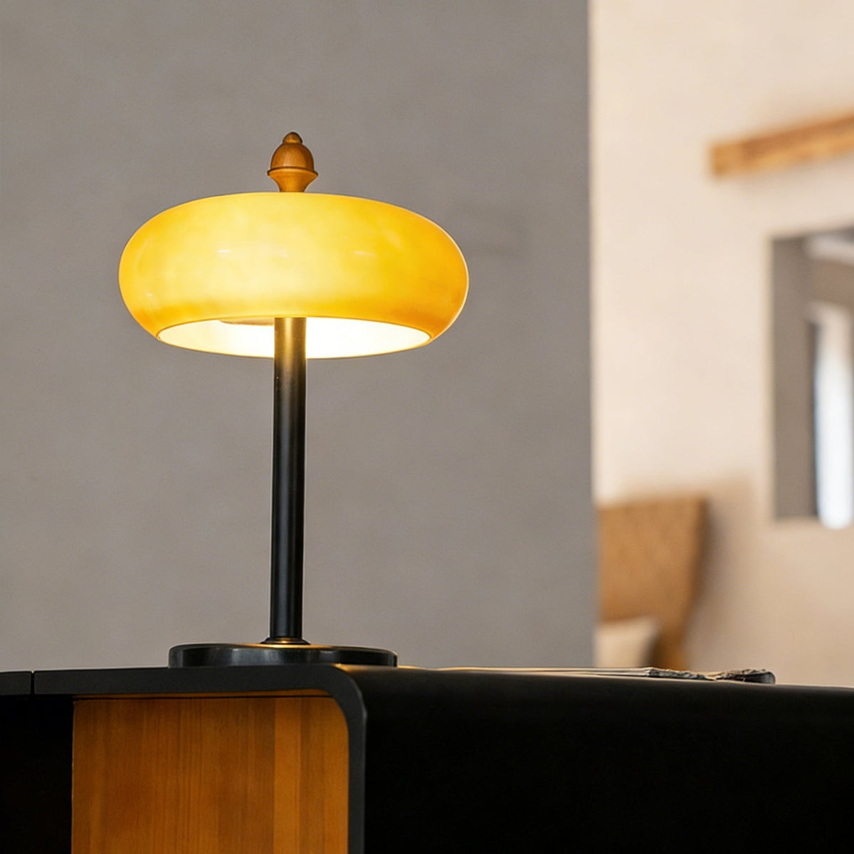 Low angle on the lit Clérachic lamp, showing the glowing dome and the open underside of the shade above the black stem.