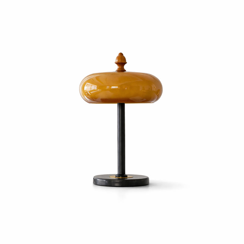 This Clérachic caramel glass lamp cut out on a white ground, with a brown-amber dome, black stem and low round base.