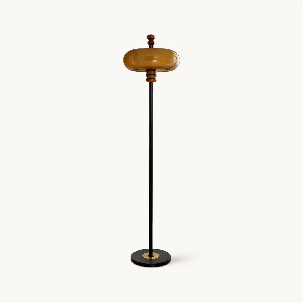 Clérachic floor lamp with a caramel glass shade, wooden collar, slim black stem and round black base, unlit on a plain white backdrop.