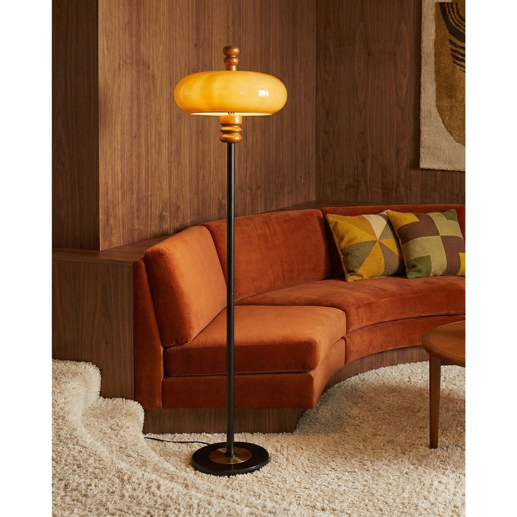 A lit caramel glass shade glows beside a rust velvet curved sofa on a shaggy cream rug, from this Clérachic floor lamp.