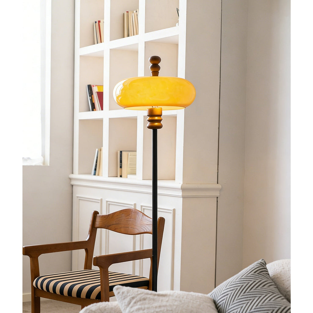 The caramel glass shade glows bright yellow-orange beside white shelving and a wooden chair with a striped seat, from Clérachic.
