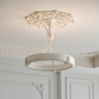 Seen from below, this Clérachic chandelier hangs from a carved plaster ceiling rose above panelled white walls and a fluted cornice.