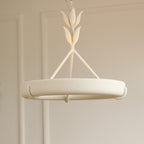 Front view of the white plaster ring held by three rods and a leaf-bud stem, against a warm beige wall, on a Clérachic chandelier.
