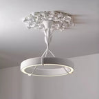 Lit white plaster ring below a ruffled plaster ceiling rose, with a soft glow along its inner edge; a Clérachic chandelier against a grey wall.