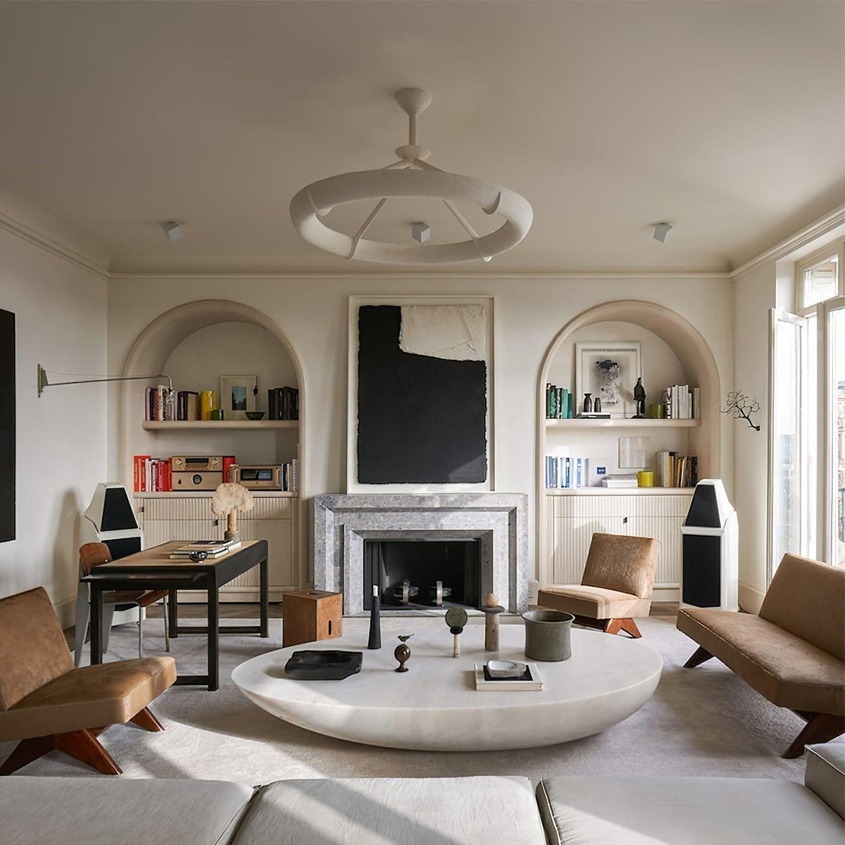 Seen across a large living room with arched shelves and a low stone coffee table, this Clérachic chandelier hangs near the centre of the ceiling.