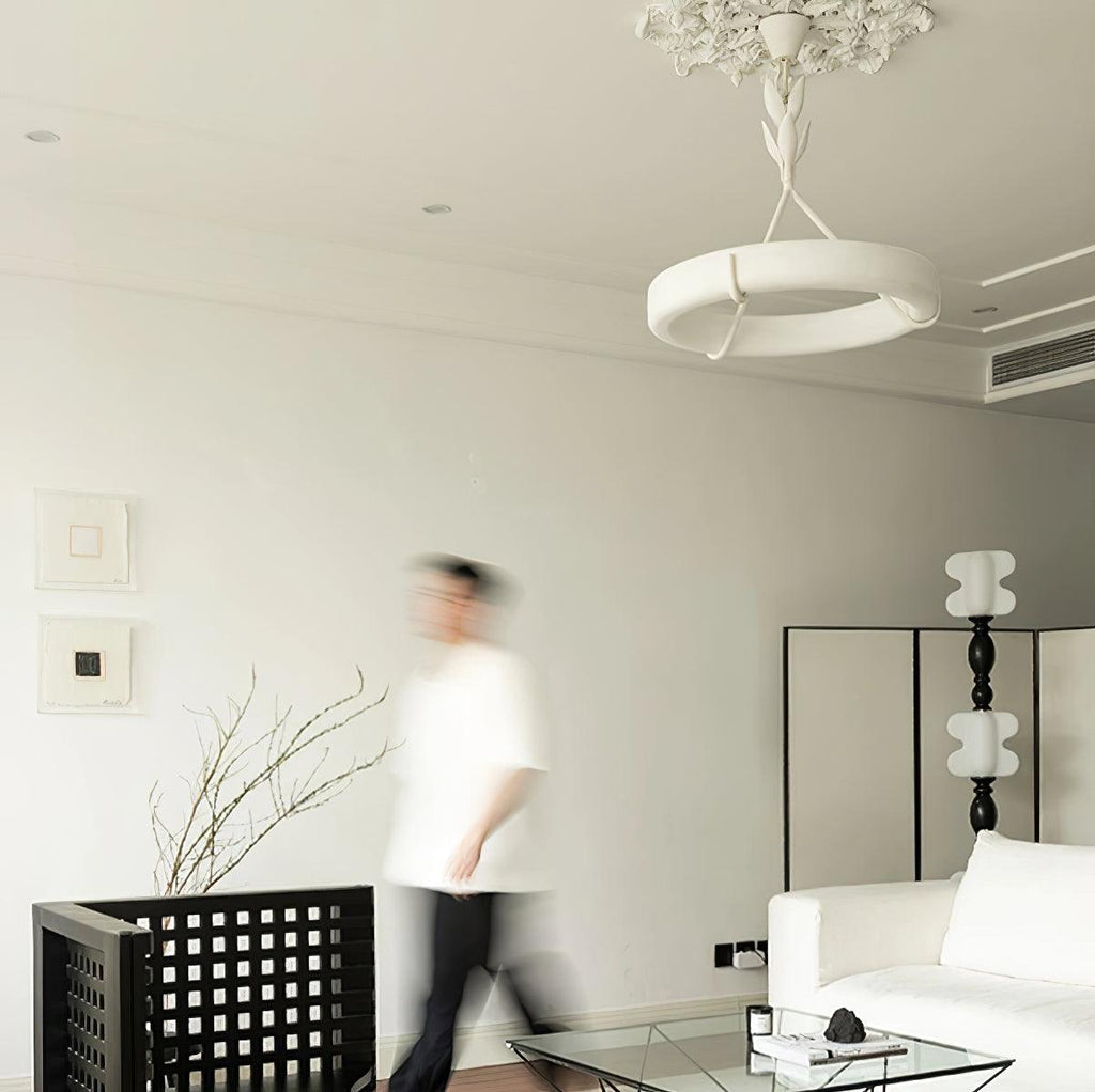 A blurred figure walks through a pale room beneath this Clérachic chandelier, which hangs from a decorative plaster rose.