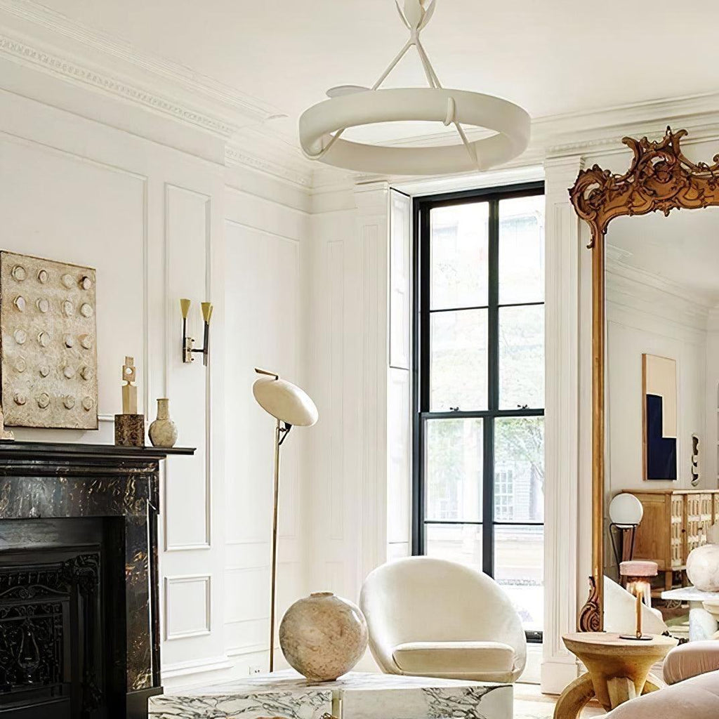 Bright panelled room with a black marble fireplace, a tall gilded mirror and a white arc lamp; this Clérachic chandelier hangs high above.