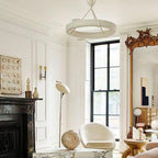 Bright panelled room with a black marble fireplace, a tall gilded mirror and a white arc lamp; this Clérachic chandelier hangs high above.