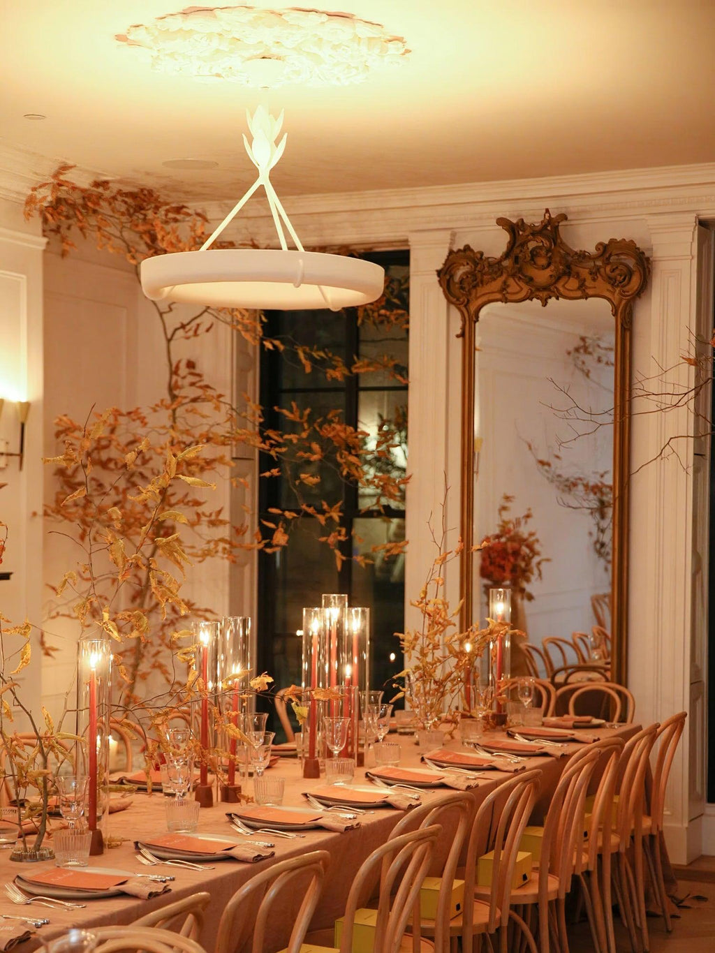 Candlelit dining table with autumn branches and a gilded mirror, with this Clérachic chandelier glowing softly overhead.