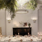 Close view of the white ring glowing under hanging greenery, above a candlelit table and a black fireplace; a Clérachic chandelier.