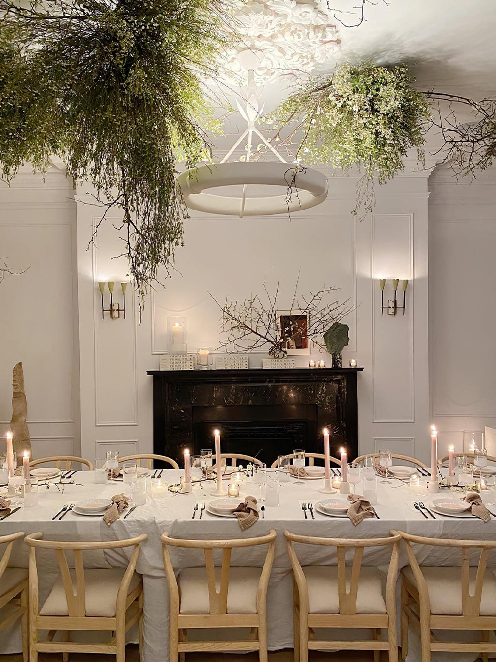 Dining room dressed with candles and light wood chairs, and this Clérachic chandelier hanging among branches overhead.