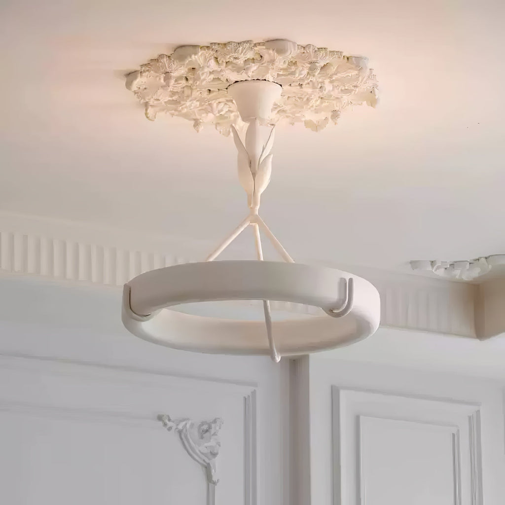 Warm ceiling light spills over the plaster rose and white ring of this Clérachic chandelier, with panelled doors behind.