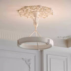 Warm ceiling light spills over the plaster rose and white ring of this Clérachic chandelier, with panelled doors behind.