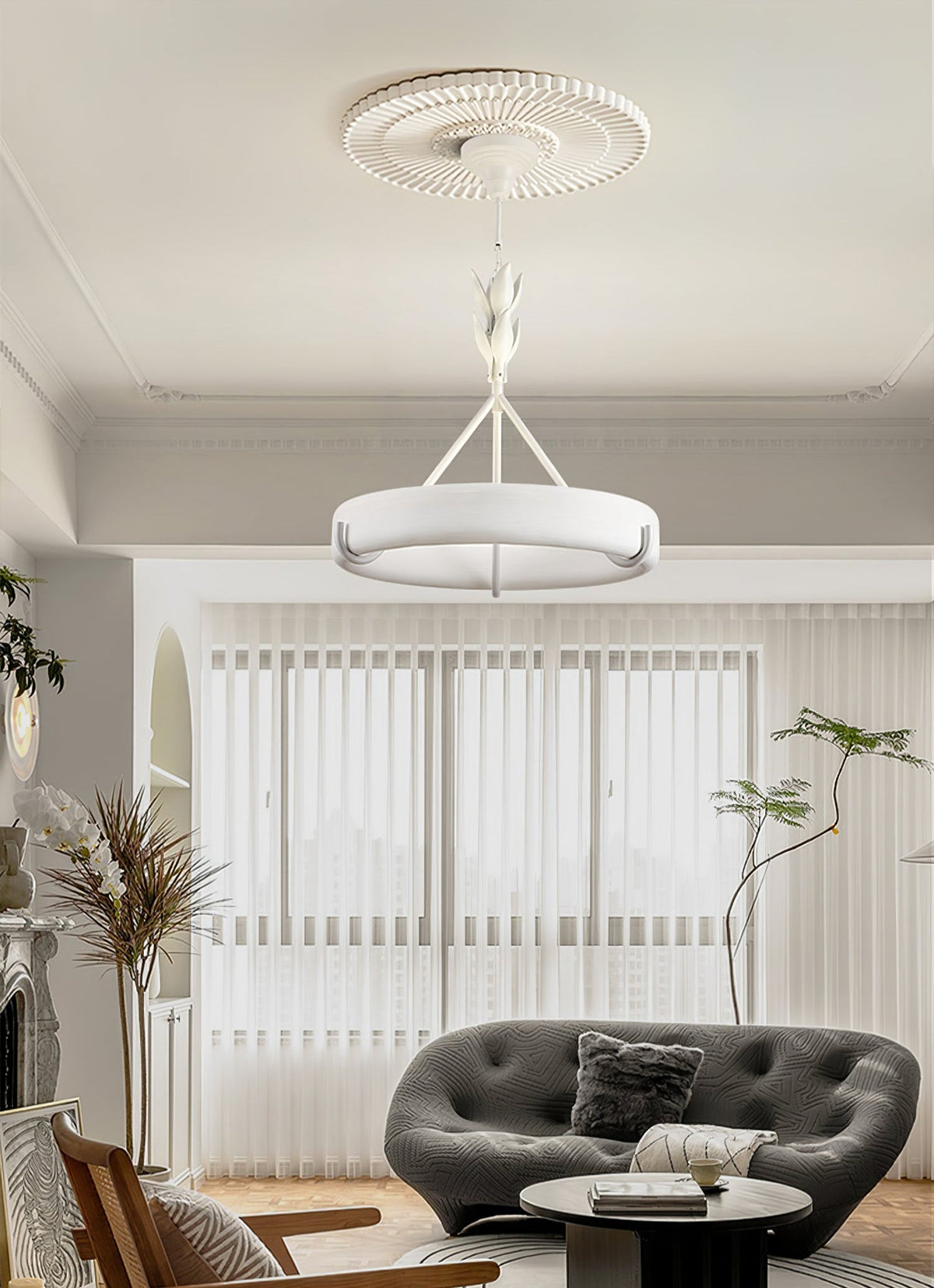 Large window with sheer vertical blinds and a grey sofa below this Clérachic chandelier, which hangs from a ribbed ceiling rose.