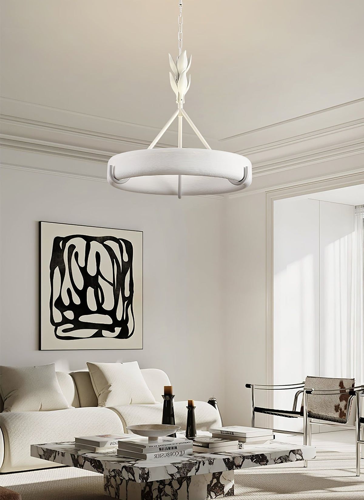 A white sofa, a marble coffee table and an abstract black-and-white print sit below this Clérachic chandelier in a bright, moulded room.