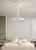 Above a bed with a cream headboard in a green and white panelled room, this Clérachic chandelier hangs from a ribbed ceiling rose.