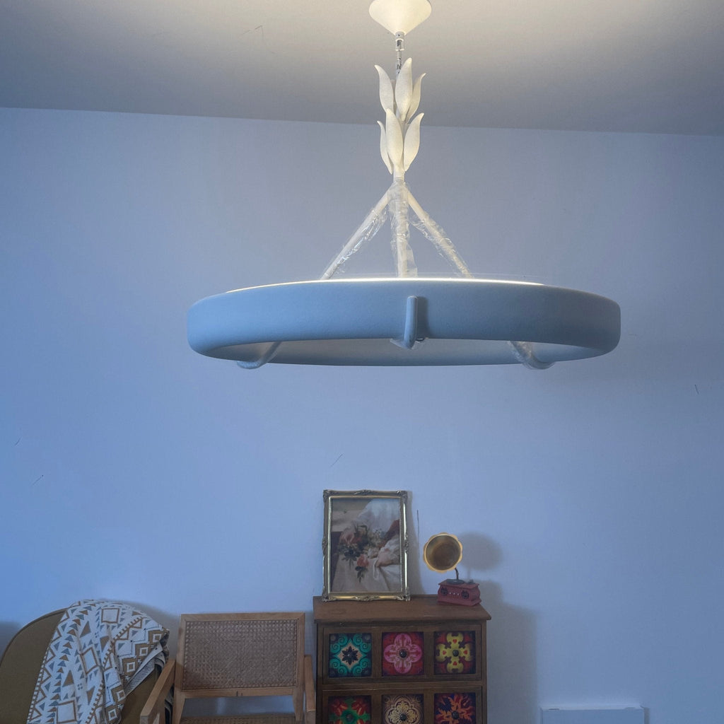 Home snapshot of the white ring from below, tinted blue by cool daylight, above a painted wooden cabinet; a Clérachic chandelier.