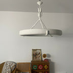 Customer-style photo of the white ring in neutral daylight, with a framed picture and a retro gramophone below; a Clérachic chandelier.
