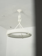 View from below the ring against a white wall, with a dark shadow edge on the right; a Clérachic chandelier.
