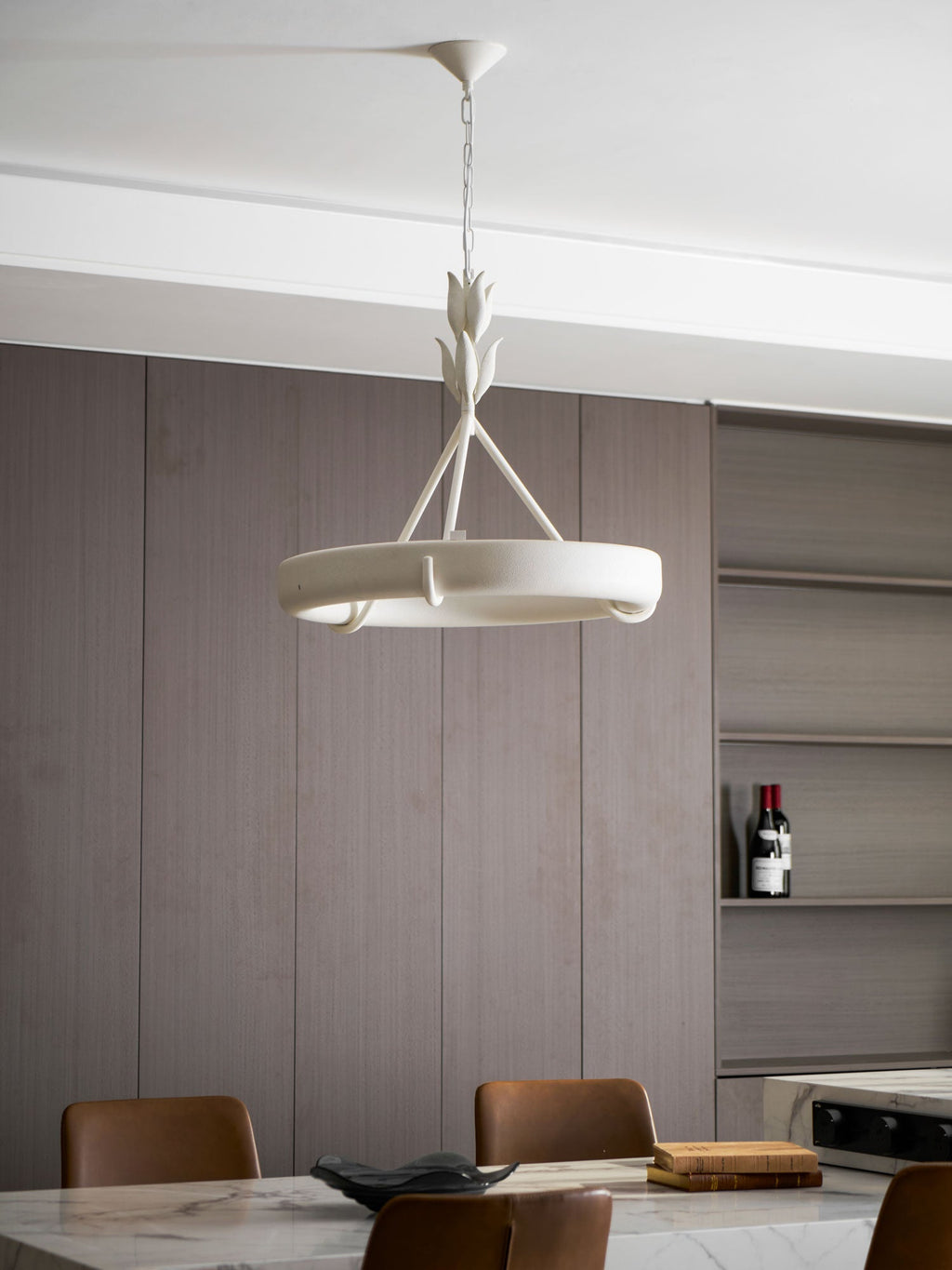 Kitchen-diner with walnut-toned panelling and tan leather chairs at a marble island, with this Clérachic chandelier hanging above.