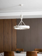 A Clérachic chandelier hangs in front of a ribbed wood wall and a marble table, with the chair backs just visible below.