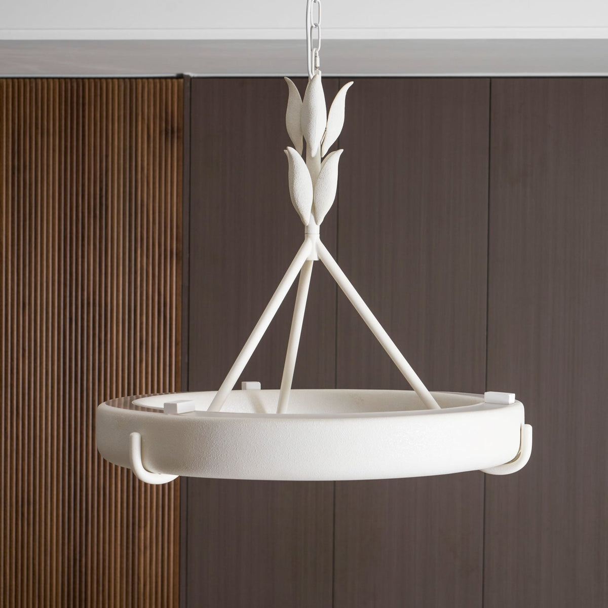 Close view of the textured white leaf buds, three rods and ring, against a ribbed walnut wall; a Clérachic chandelier.